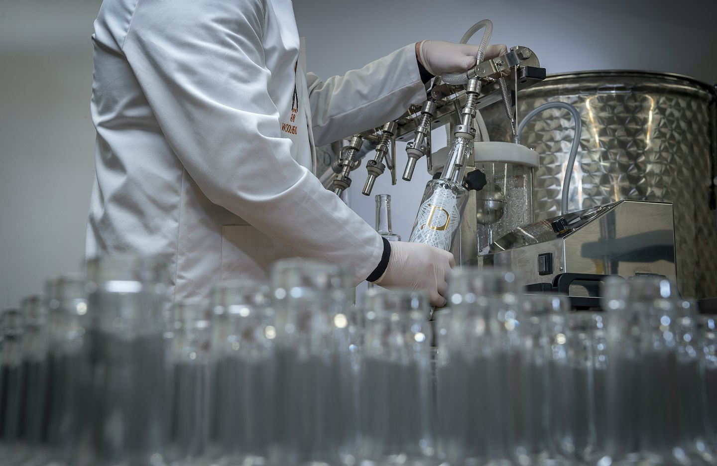 Obrero llenando botellas en una línea de producción.