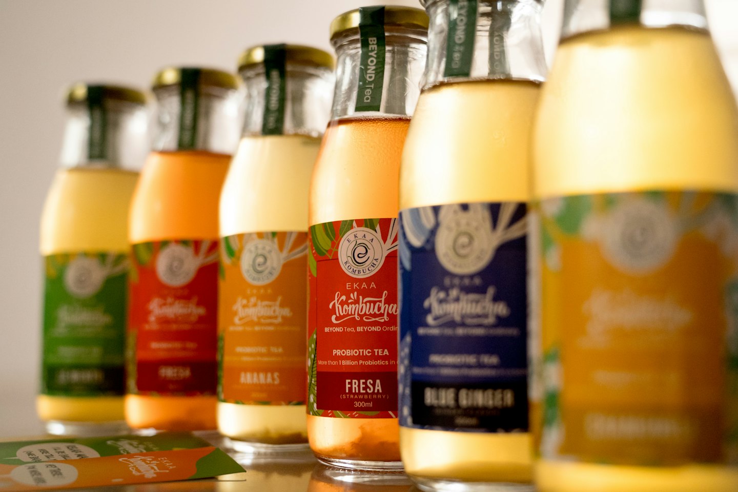 Botellas de vidrio de colorida kombucha en fila sobre una superficie.