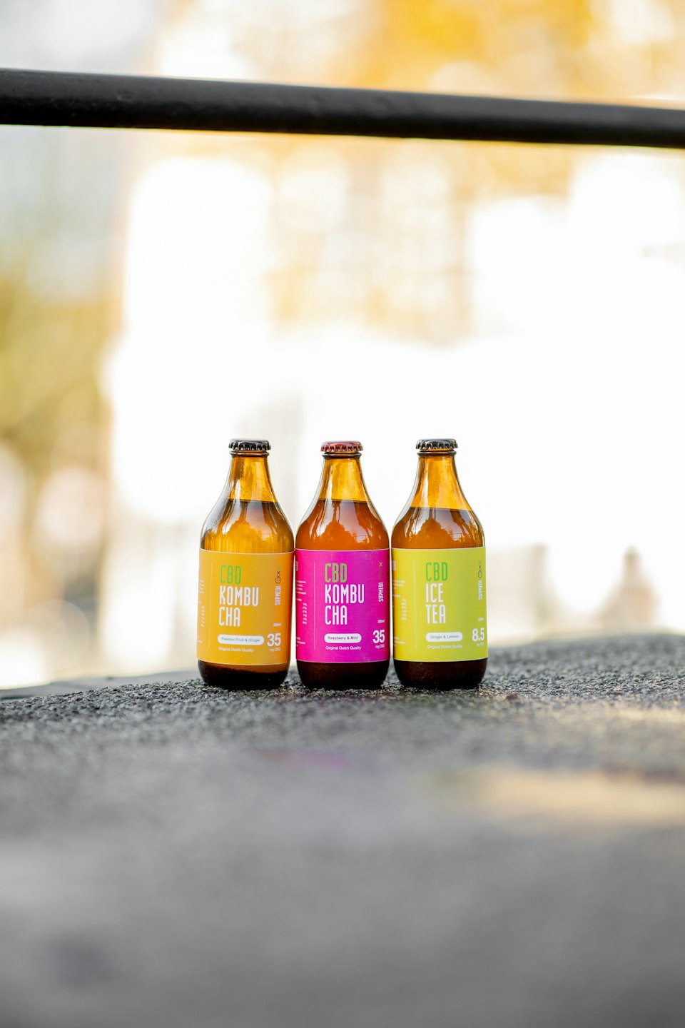 Tres coloridas botellas de bebidas con infusión de CBD sobre una superficie gris.